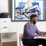 Xerox® VersaLink® C415 Multifunction Printer en situation au travail Hommes travaillant sur un ordinateur portable devant une Imprimante couleur multifonctions Xerox® VersaLink® C415