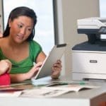 Xerox® VersaLink® B415 Multifunction Printer en situation au travail Deux femmes utilisant une tablette devant une imprimante multifonction Xerox® VersaLink® B415