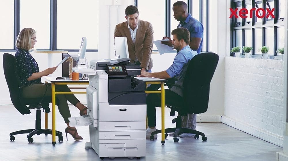 Employés de bureau collaborant à proximité d'une imprimante Xerox.